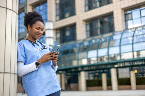 istock Smiling doctor leaning against a column and using a smartphone 2204968129