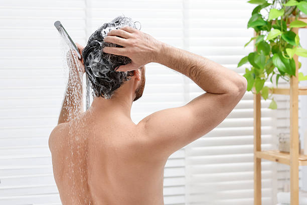 istock Man washing his hair with shampoo in bathroom, back view 2204970903