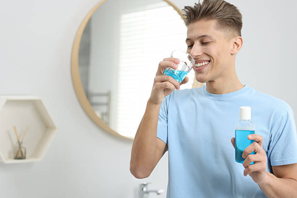 istock Young man using mouthwash in bathroom. Oral hygiene 2204971629