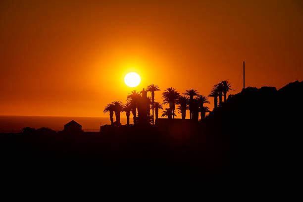 A breathtaking sunset at St. Vicente Lighthouse in California, where the golden light casts a warm glow over the rugged cliffs and the Pacific Ocean sparkles in the fading day.