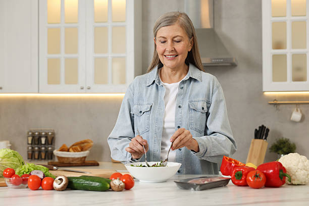 istock Happy woman making salad at table in kitchen 2204972138