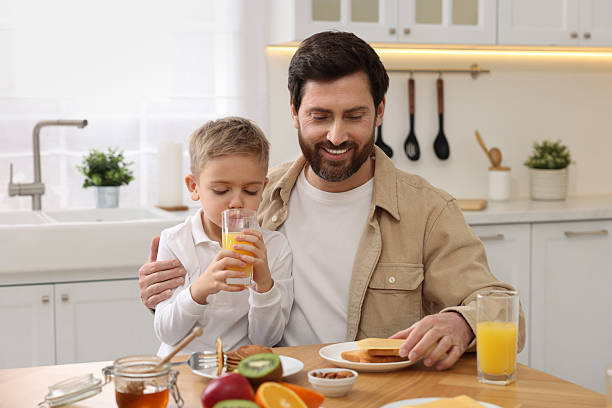 istock Father and his cute little son having breakfast at table in kitchen 2204972223