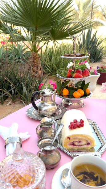 Creamy cake roll placed next to cup on wooden table, ornate silver tray adding rustic elegance. Cup and cake together enhance outdoor dessert ambiance. Wooden display concept.