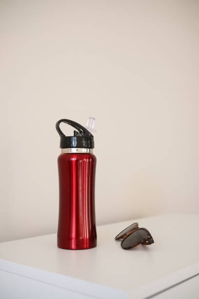 istock A striking Red Metal Water Bottle and stylish sunglasses placed on a clean White Surface 2204975517
