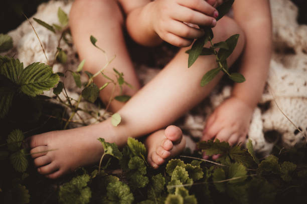 Child sitting in the dirt and grass with dirty bare feet and toes