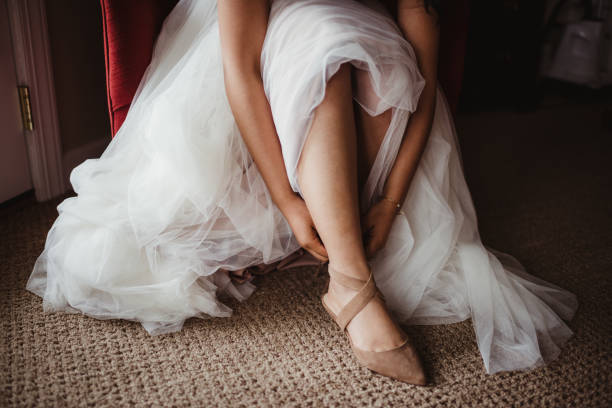 istock Bride putting on strappy high heels in wedding dress 2204979943