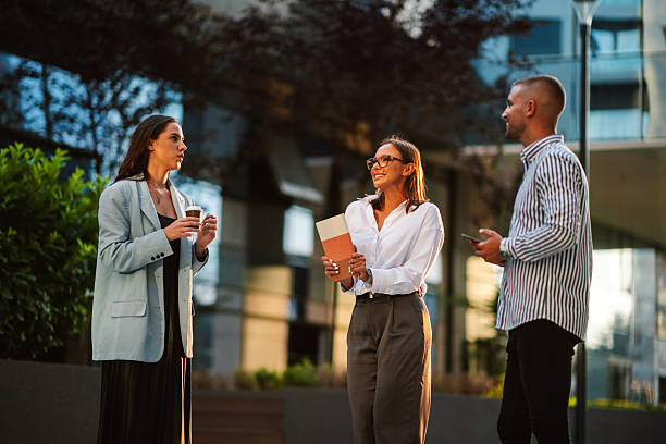 istock Three business people having informal meeting while standing outside office building 2204982814