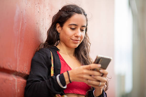 istock young woman standing by wall with cellphone 2204984456