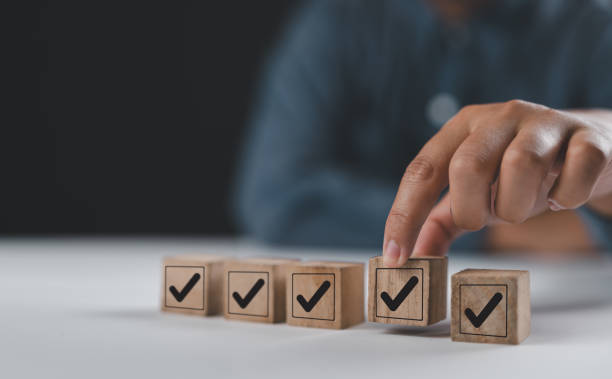 istock Corporate regulatory and compliance. Quality control management, ISO certification. Product, service quality warranty. Checklist survey and assessment process. Put wooden cube with check mark icon. 2204984993