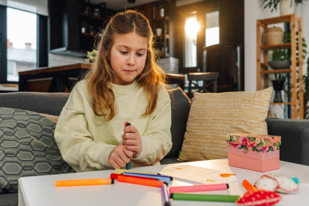 istock Elementary age girl drawing with markers at home 2204985972