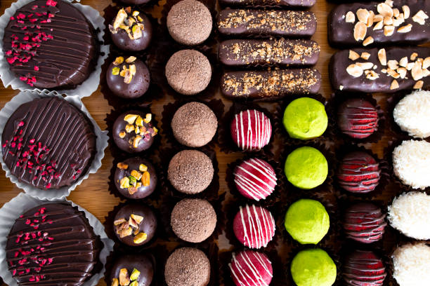 istock Assorted chocolate truffles and desserts with nuts and toppings on wooden surface 2204989054