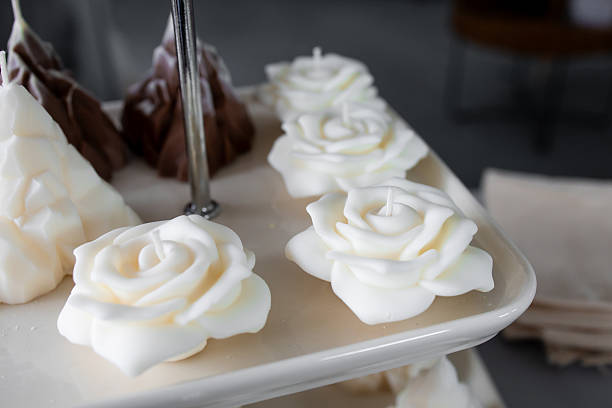 Elegant white rose shaped candles on a display stand in a cozy setting