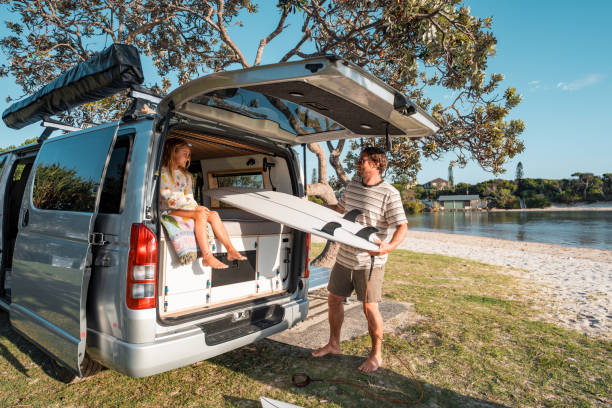 istock Father Unloading Surfboards by Camper Van Near Scenic Ocean 2204989280