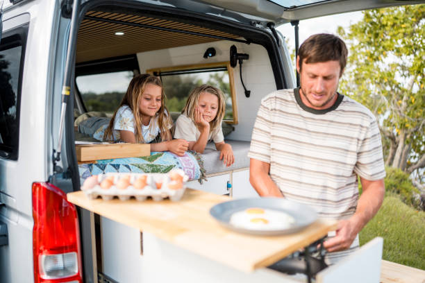 istock Father Cooking Breakfast While Daughters Watch From Camper Van 2204989378