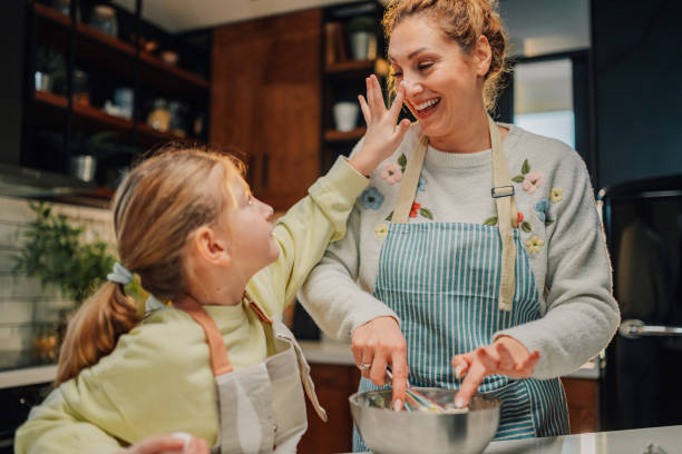 istock Daughter putting flour on her mother's nose while baking in the kitchen 2204991243