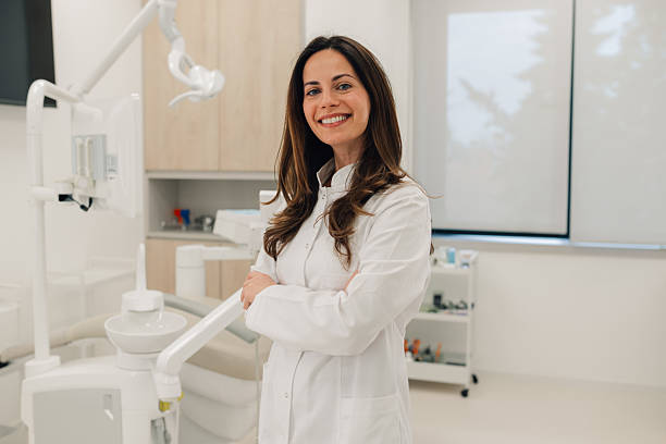 Portrait of smiling dentist standing in her modern office Confident female dentist smiling with arms crossed in her modern dental clinic dentist stock pictures, royalty-free photos  images