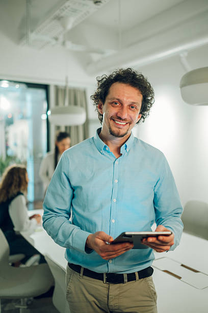 istock Smiling businessman holding digital tablet in modern office 2204991613