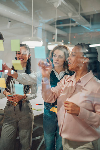 istock Businesswomen planning strategy using adhesive notes on glass wall in office 2204991641