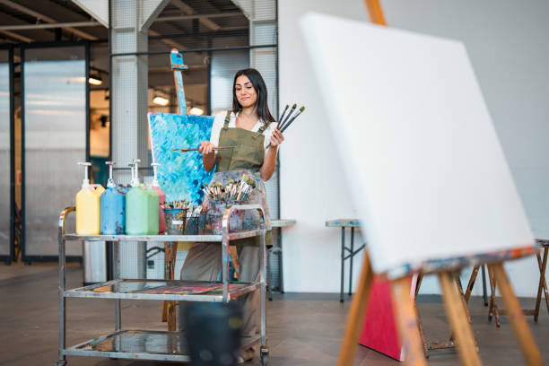 istock Young Middle Eastern Art Teacher in Studio Holding Brushes with Bright Paints and Canvas 2204993712