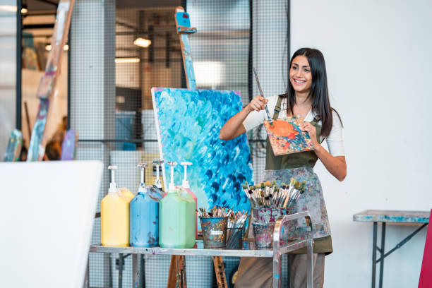 istock Smiling Middle Eastern Art Teacher in Apron Painting in Bright Studio 2204993740