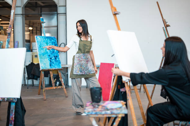 istock Young Middle Eastern Art Teacher Guiding Students in Bright Studio Setting with Vibrant Paintings 2204993741