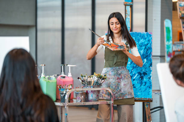 istock Enthusiastic Art Teacher Demonstrates Techniques While Students Observe In Bright Studio Space 2204993750