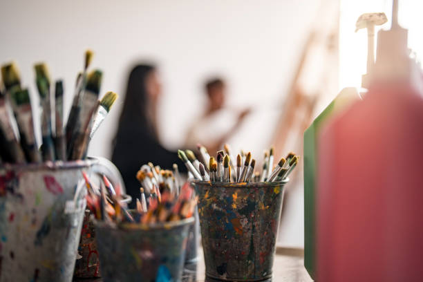 Art Class Supplies with Paintbrushes and Students in Bright Creative Studio
