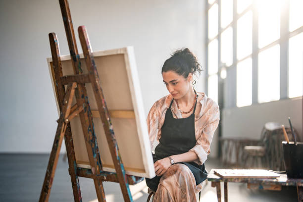 istock Creative Middle Eastern Female Artist Painting in Bright Sunlit Studio 2204993902
