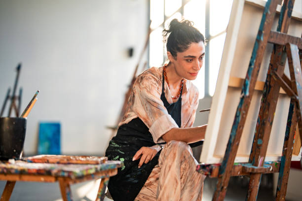 istock Young Middle Eastern Female Artist Painting in a Bright, Sunlit Studio 2204993905