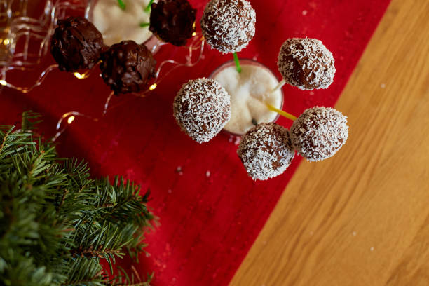 istock Chocolate cake pops with coconut shavings are displayed in a glass at a celebration, surrounded by festive decorations. 2204994953