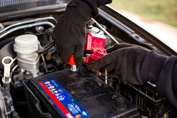istock Replacing a car battery. A man installs a battery by putting terminals on the current terminal under the hood of a car 2204995317