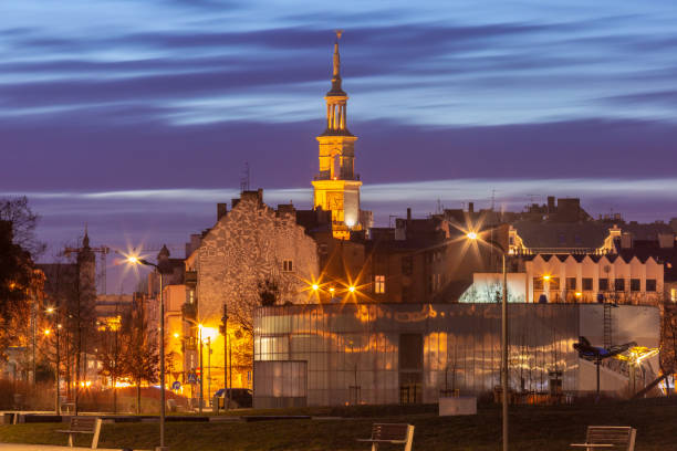 Evening cityscape in Poznan, Poland, featuring the illuminated tower of a historic building against a twilight sky
