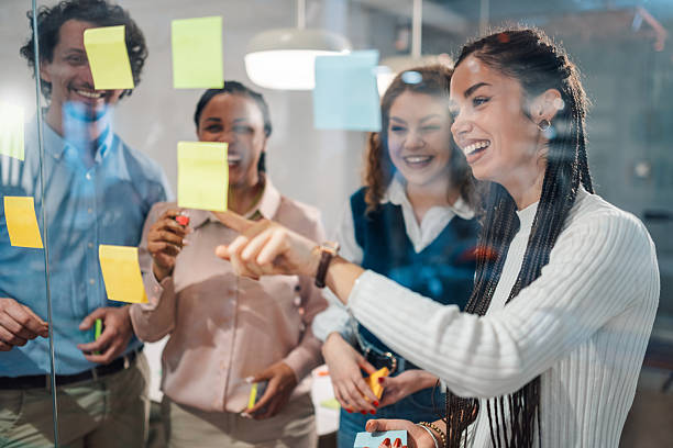 istock Smiling business team brainstorming with sticky notes on glass wall in office 2205001257