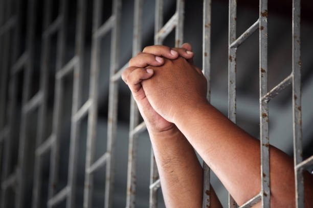 istock Hands Grasping Metal Bars in Jail Cell Symbolizing Confinement 2205004075
