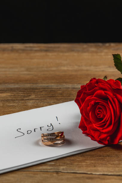 istock Broken engagement symbolized by a note and rings beside a red rose 2205004603