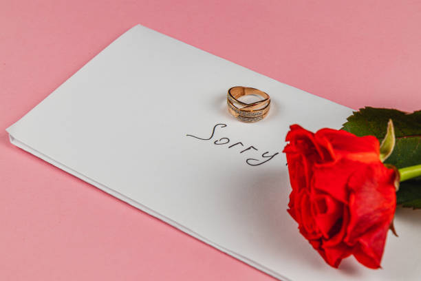 istock Broken engagement ring and red rose with a sorry note on a pastel background 2205005033