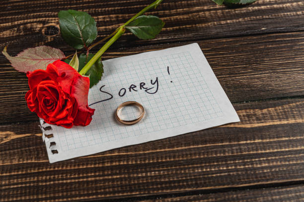 istock Broken engagement reflected with a wilted rose and a ring on a handwritten note 2205006057