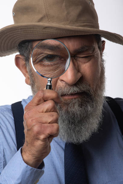 istock Detective looking through magnifying glass on white background 2205011886