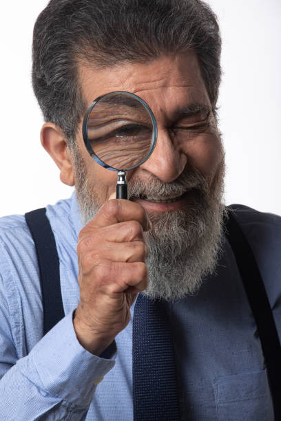 istock Detective looking through magnifying glass on white background 2205011893