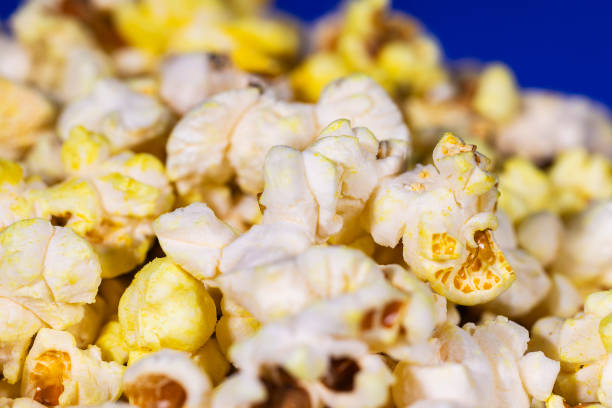 Bowl full of healthy butter popcorn on blue background, high resolution image