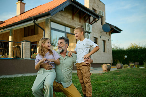 istock Grandfather holding grandchildren while playing in backyard 2205019942