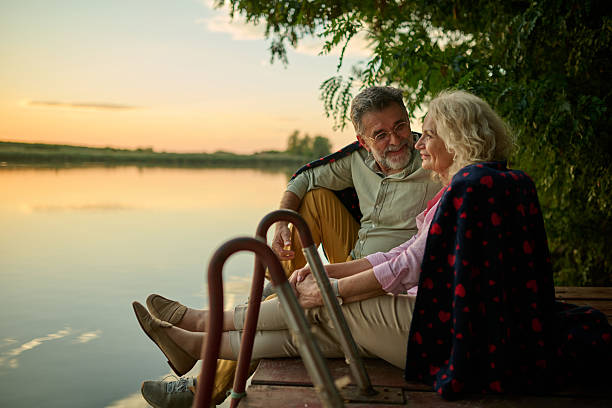 istock Senior couple relaxing on lake pier at sunset 2205019979