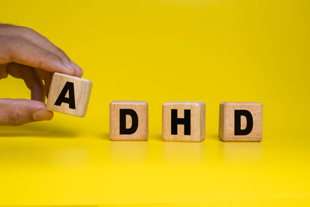 istock male hand put wooden blocks with ADHD or attention deficit hyperactivity disorder symbol isolated on yellow background 2205022415