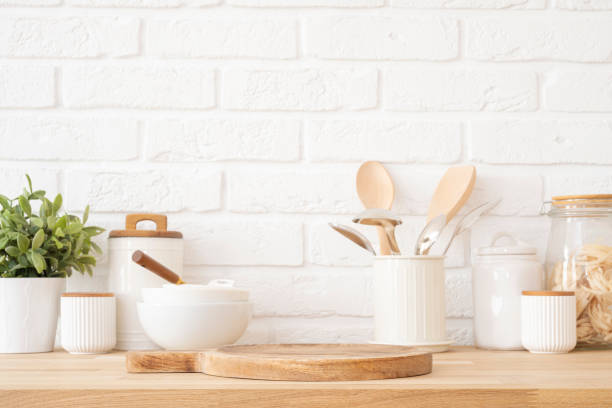 istock Table top with dish podium board on background of white brick wall and kitchen utensils 2205022926
