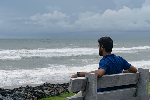 A person man sitting on a bench and watching sea waves at a beach. Thinking, future, calm, peaceful, refresh, breathe, meditation, tension, stress, relax, chill, solitude, hopeful, family, exam, job