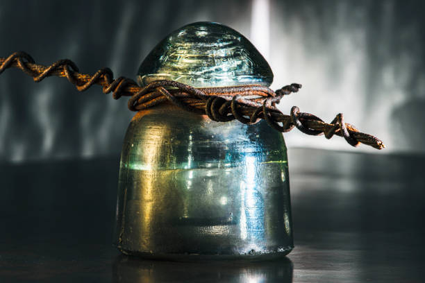 On the shelf are gold-colored glass insulators for high-voltage electric poles. Storage of materials for electrification in a warehouse