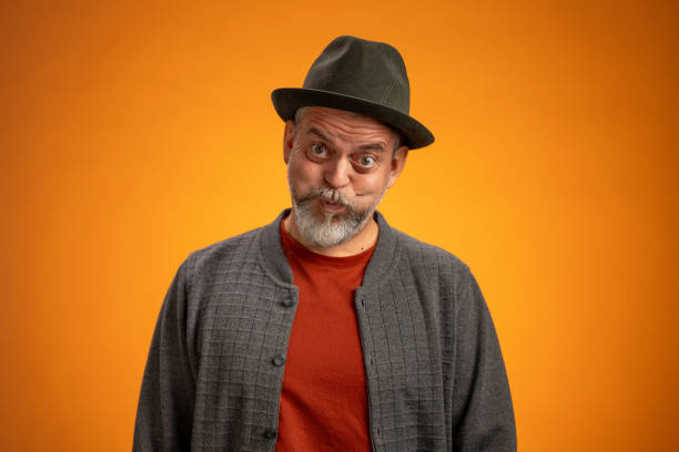 istock Funny Mature Man in Hat Against Bright Orange Background 2205028179