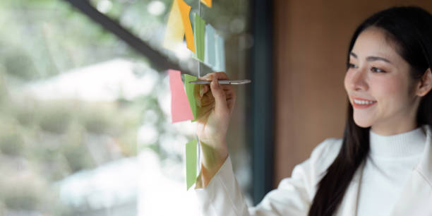 istock Female professional writing on sticky notes while brainstorming ideas in a modern office setting. 2205030337