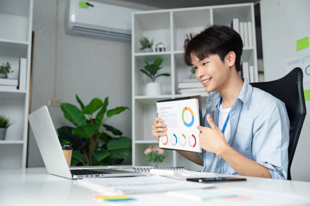 istock Young business professional analyzing data and engaging in a virtual meeting with a tablet in a modern office. 2205031310