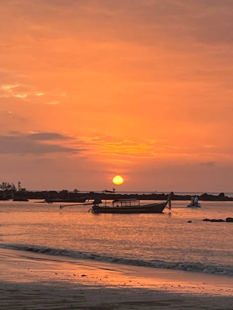 istock Traditional long-tail boat at sunset over calm ocean 2205032142